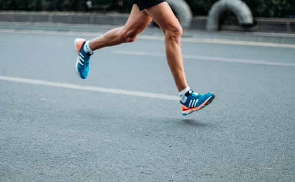 Legs of a runner running down a road. 